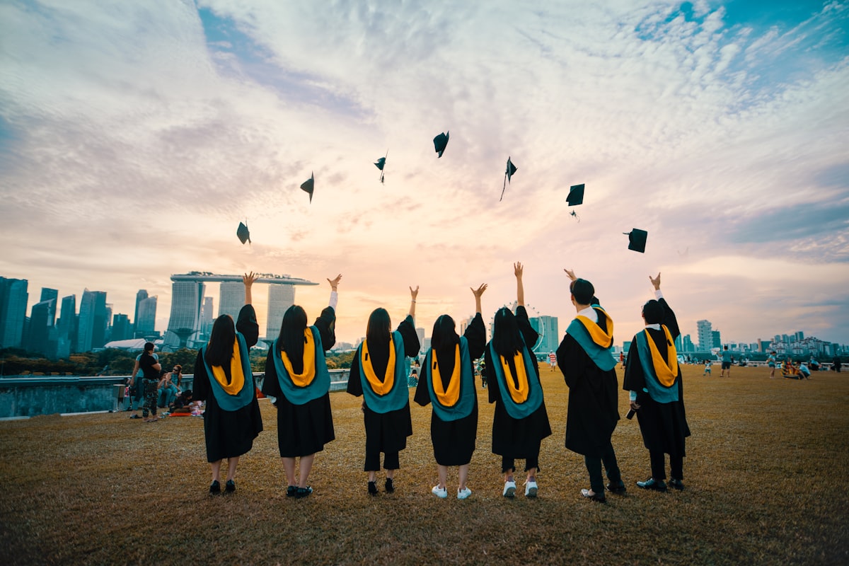 Students in graduation gowns throwing caps in the air
