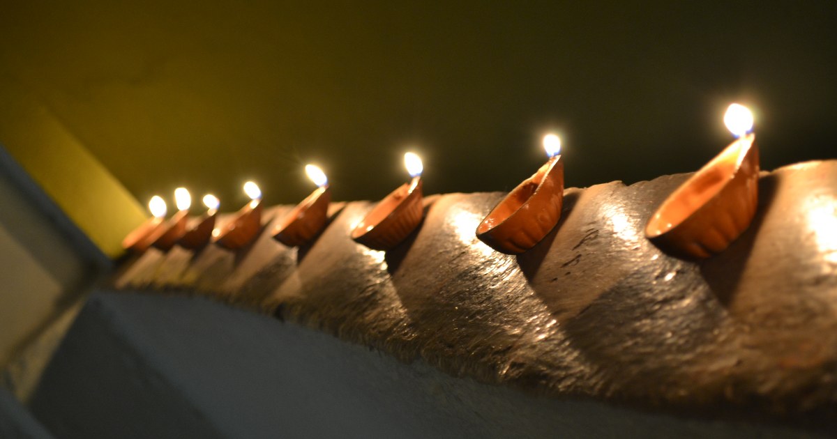 A row of lit clay diya oil lamps for Diwali